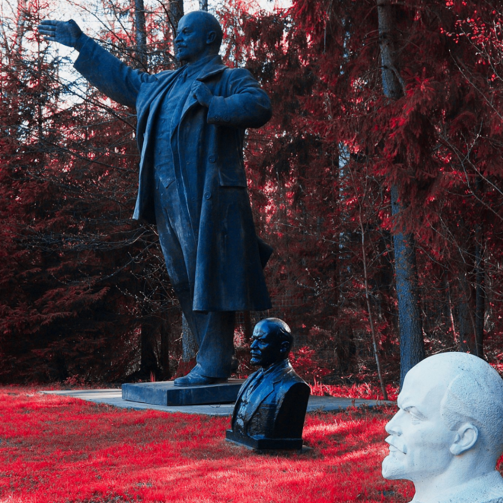 Statue of Lenin extending his hand surrounded by busts of Lenin on the ground at Grūto parkas in Lithuania
