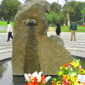 Statue in Peru of circles of pebbles in the middle of park with hunched figure in centre