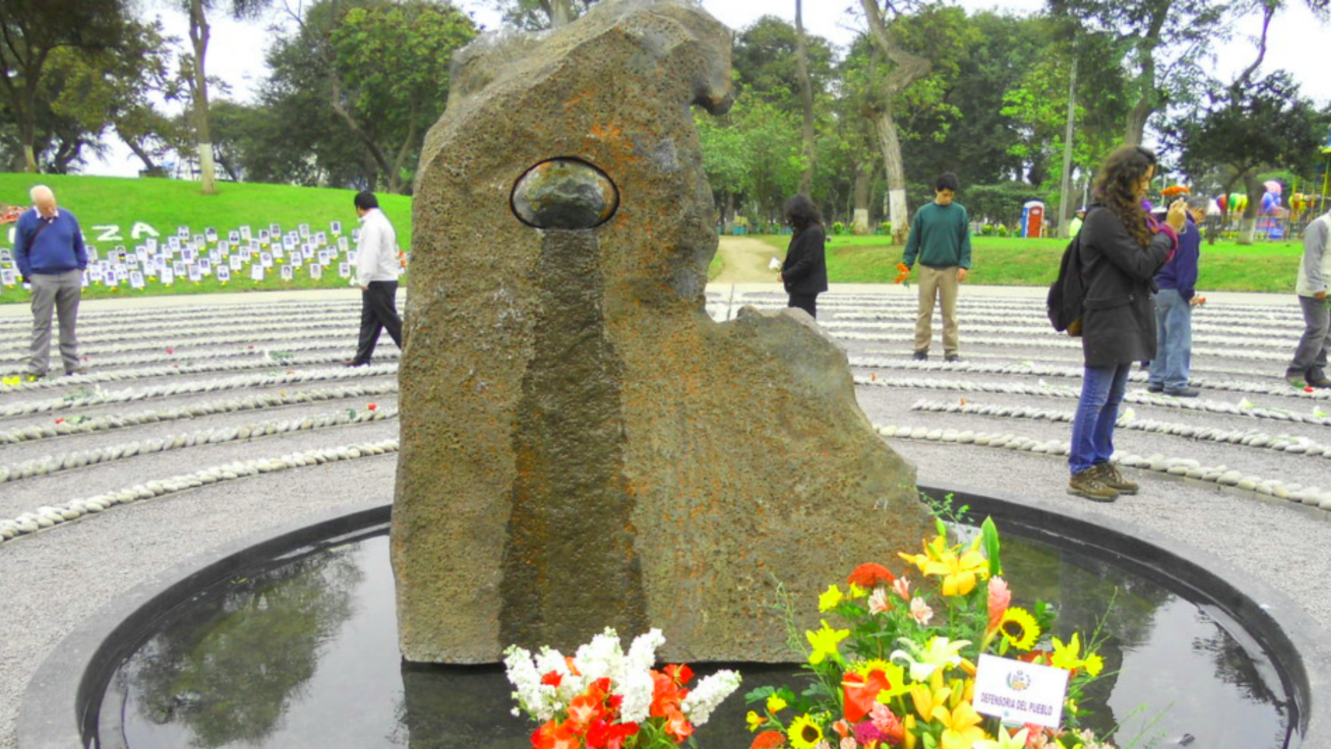 Statue in Peru of circles of pebbles in the middle of park with hunched figure in centre