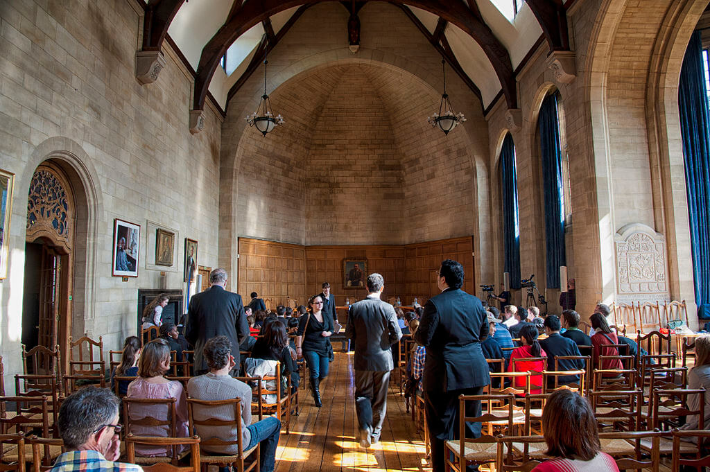 People seated and walking around Rhodes House Hall, Oxford