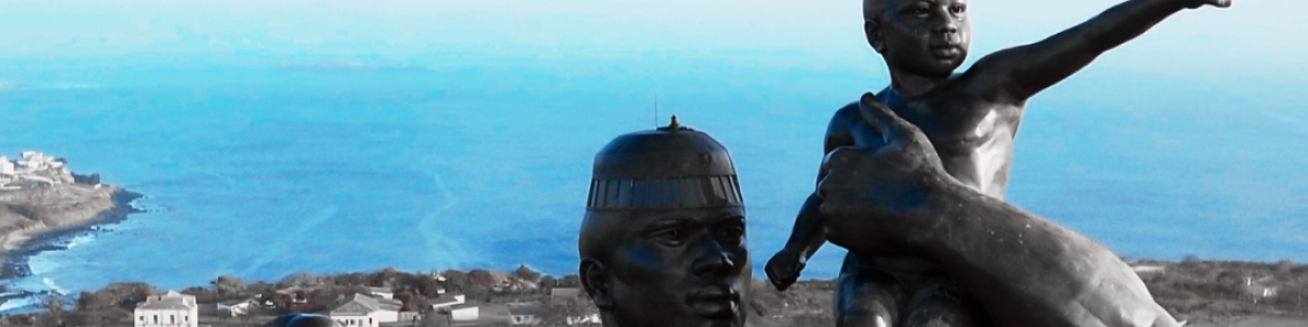 Statue of Women and Man holding a child elevated above the Dakar Skyline