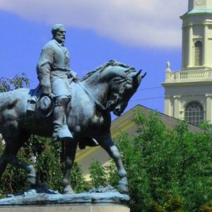 With a church spire in the background, Robert E. Lee's equestrian statue stands in a public park.