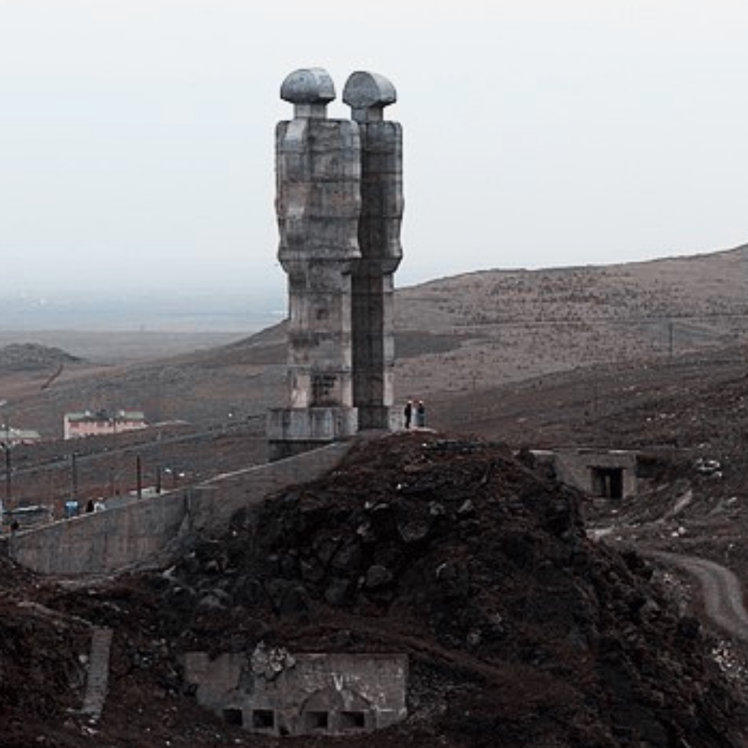 Two statues of human figures against a background of the Kars mountains