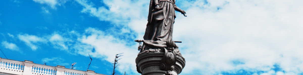 Statue of Catherine the Great in Odessa Ukraine on column with three men around base.
